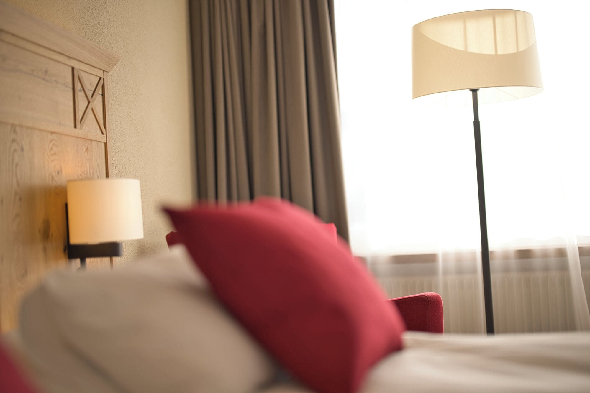 Habitación de hotel con una cama, una lámpara y un ventanal con cortinas.
