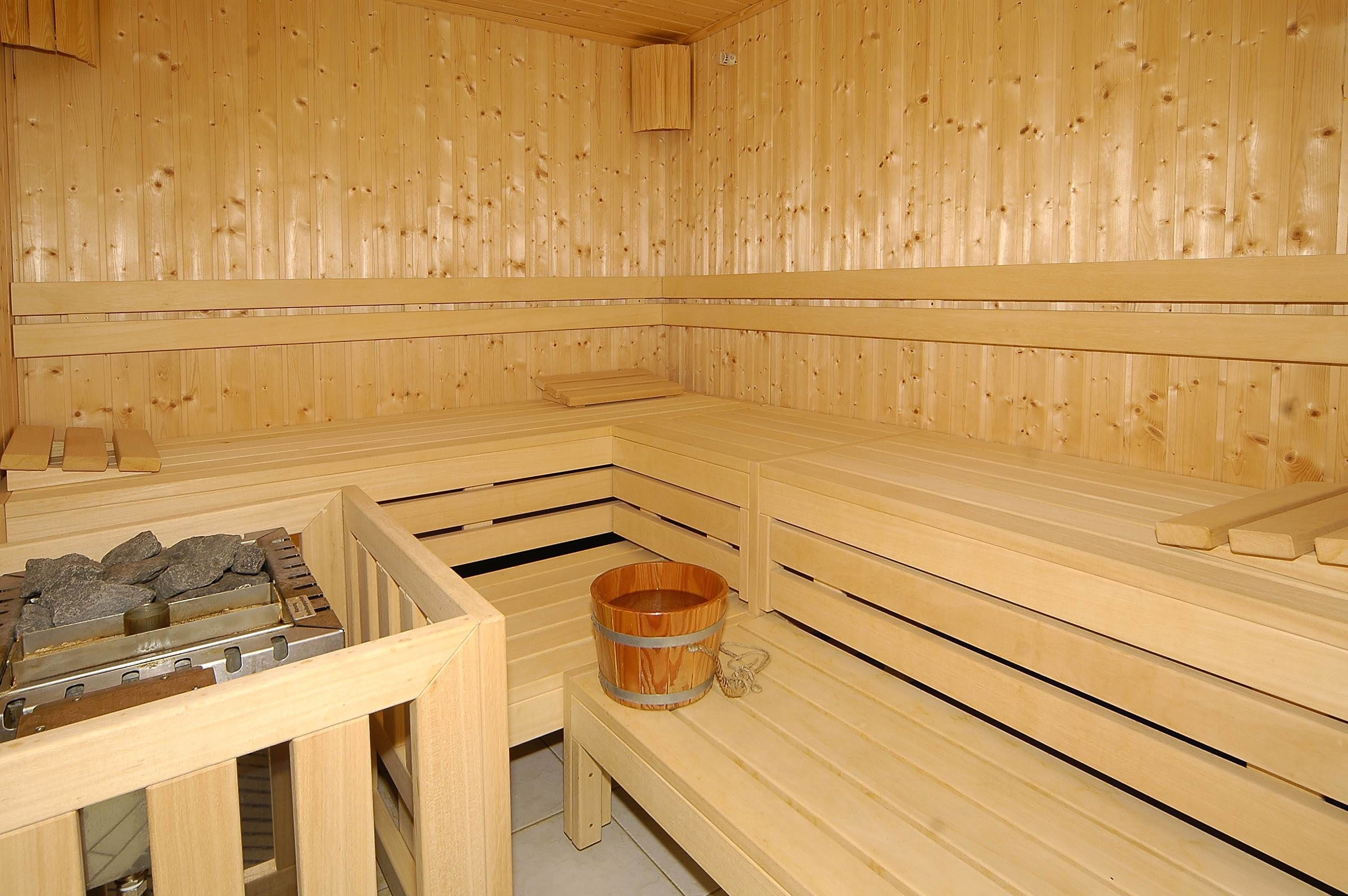 A sauna with wooden benches and a wooden bucket.