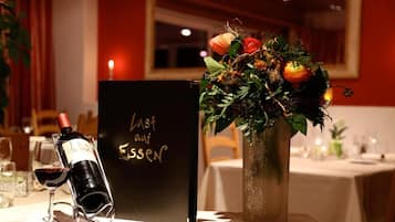A table set with a wine bottle, a glass, a menu, and a floral centerpiece.