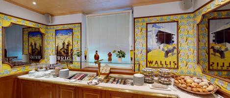 A buffet area with a variety of food items and a decorative wall with floral patterns.
