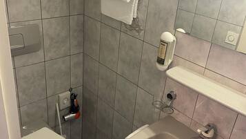 A bathroom with a toilet, sink, towel rack, and a mirror.
