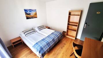 Ein Schlafzimmer mit einem Bett, einem Holzschrank, einem kleinen Nachttisch und einer Tür mit einer Nummer.