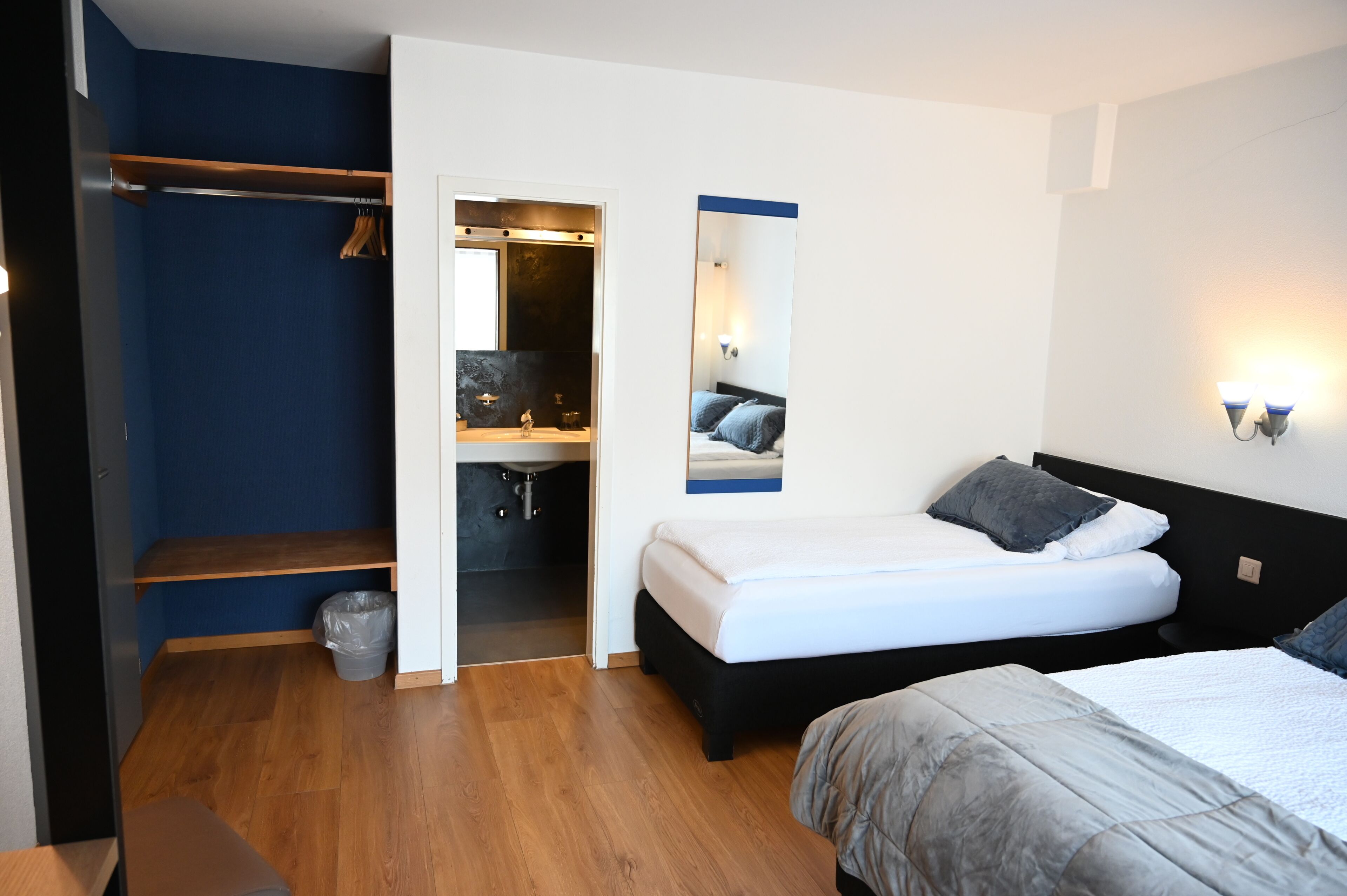 Ein Schlafzimmer mit Bett, Schrank, Spiegel und einem kleinen Badezimmer.