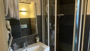 A modern bathroom with a glass-enclosed shower, a white sink, and a towel rack.