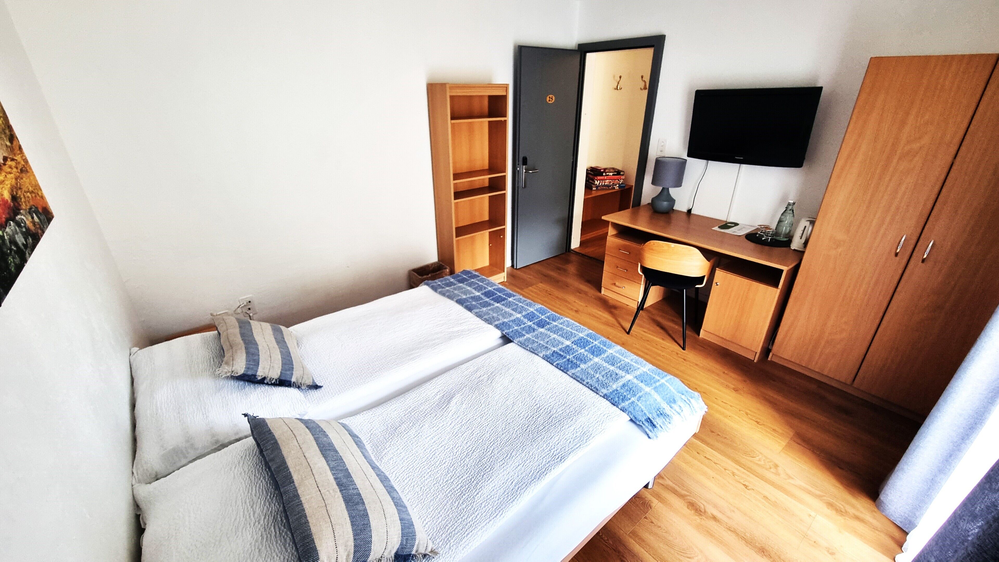 Un dormitorio con cama, escritorio, armario y televisor.