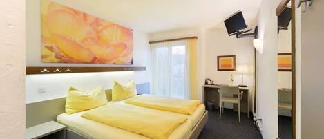 A hotel room with a bed, desk, chair, and a TV mounted on the wall.