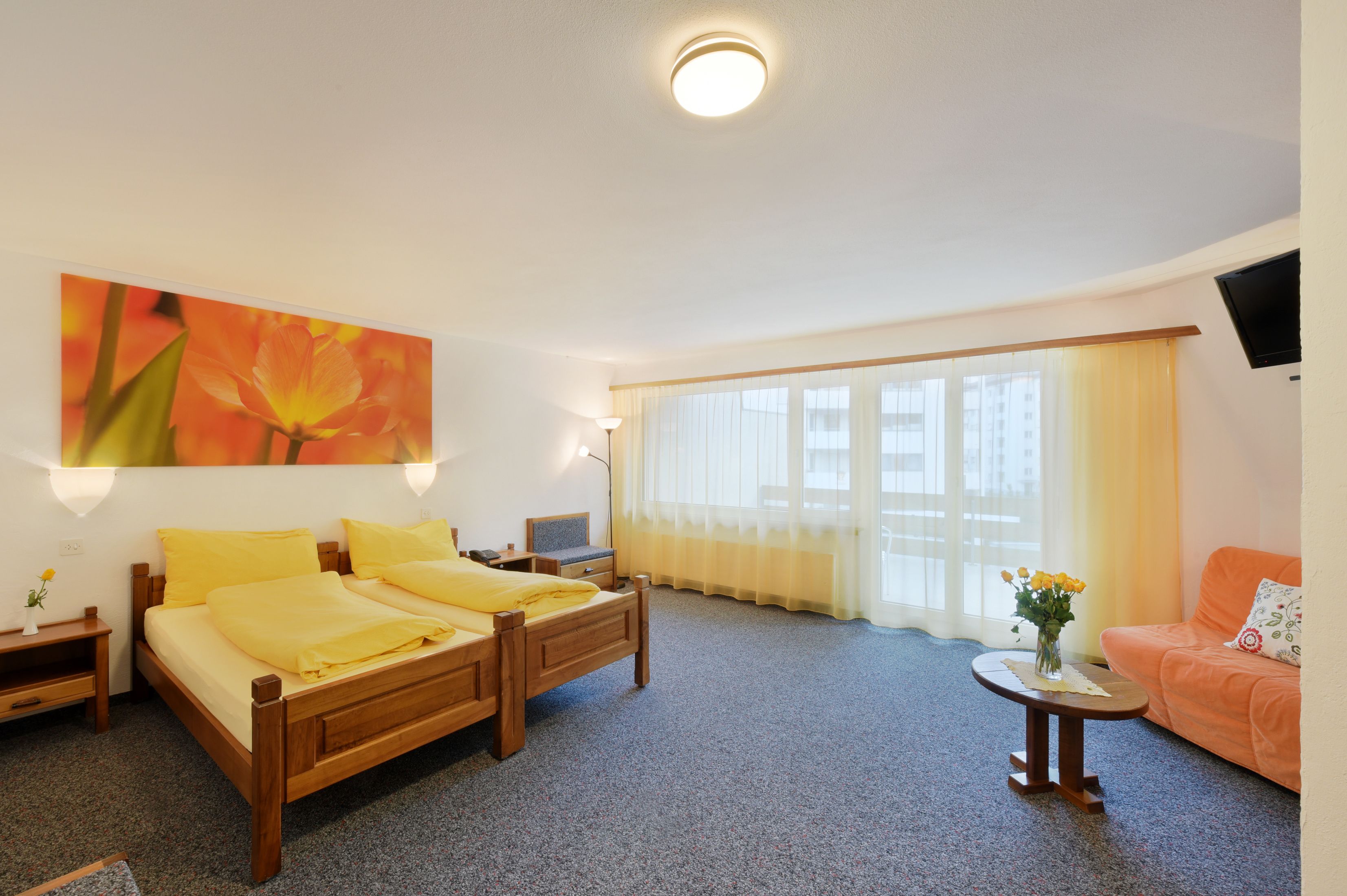 Una habitación de hotel con cama, escritorio, silla, televisor y sofá.