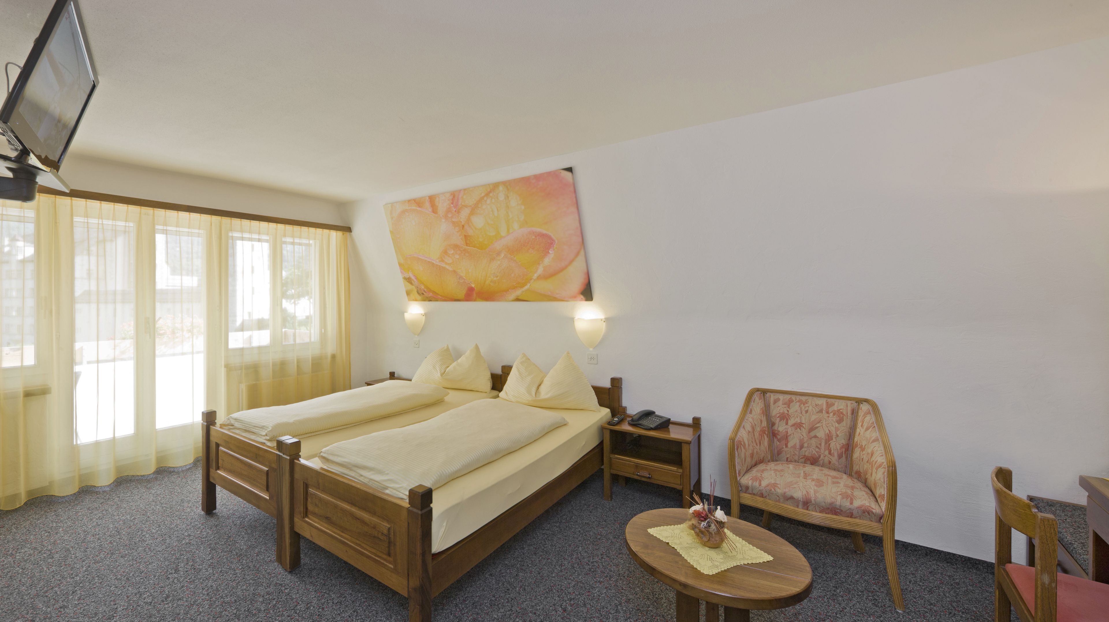 Een hotelkamer met twee bedden, een stoel, een tafeltje en een schilderij aan de muur.