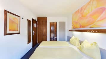 A hotel room with a bed, a large painting, and a wooden door.