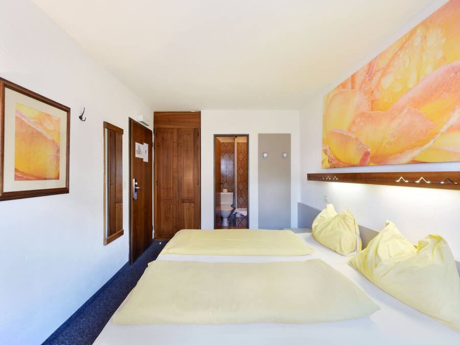 A hotel room with a bed, a large painting, and a wooden door.