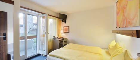 Una habitació d'hotel amb un llit, escriptori, cadira i televisió.