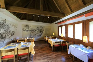 Enjoy meals in a warm and inviting dining area with tables set with white tablecloths and black and white artwork on the walls.