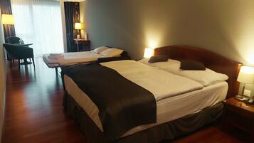 Une chambre d’hôtel avec deux lits, un bureau, une chaise et une lampe.