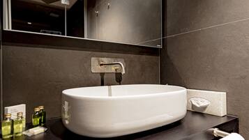 Une salle de bain moderne avec un lavabo blanc, un plan de toilette foncé et un porte-serviettes.