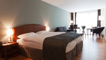 Una habitación de hotel con una cama grande, mesitas de noche, un escritorio y una silla.