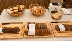 A buffet table with various breads and a toaster. - Hotel Drei Könige (Chur)