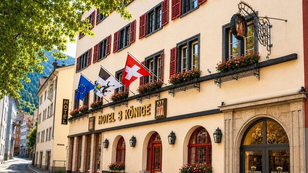 A hotel with a sign reading 'HOTEL 3 KÖNIGE,' flags, and flower boxes. - Hotel Drei Könige (Chur)