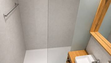 Une salle de bain moderne avec une douche à parois de verre, des toilettes blanches et un meuble-lavabo en bois avec un évier.