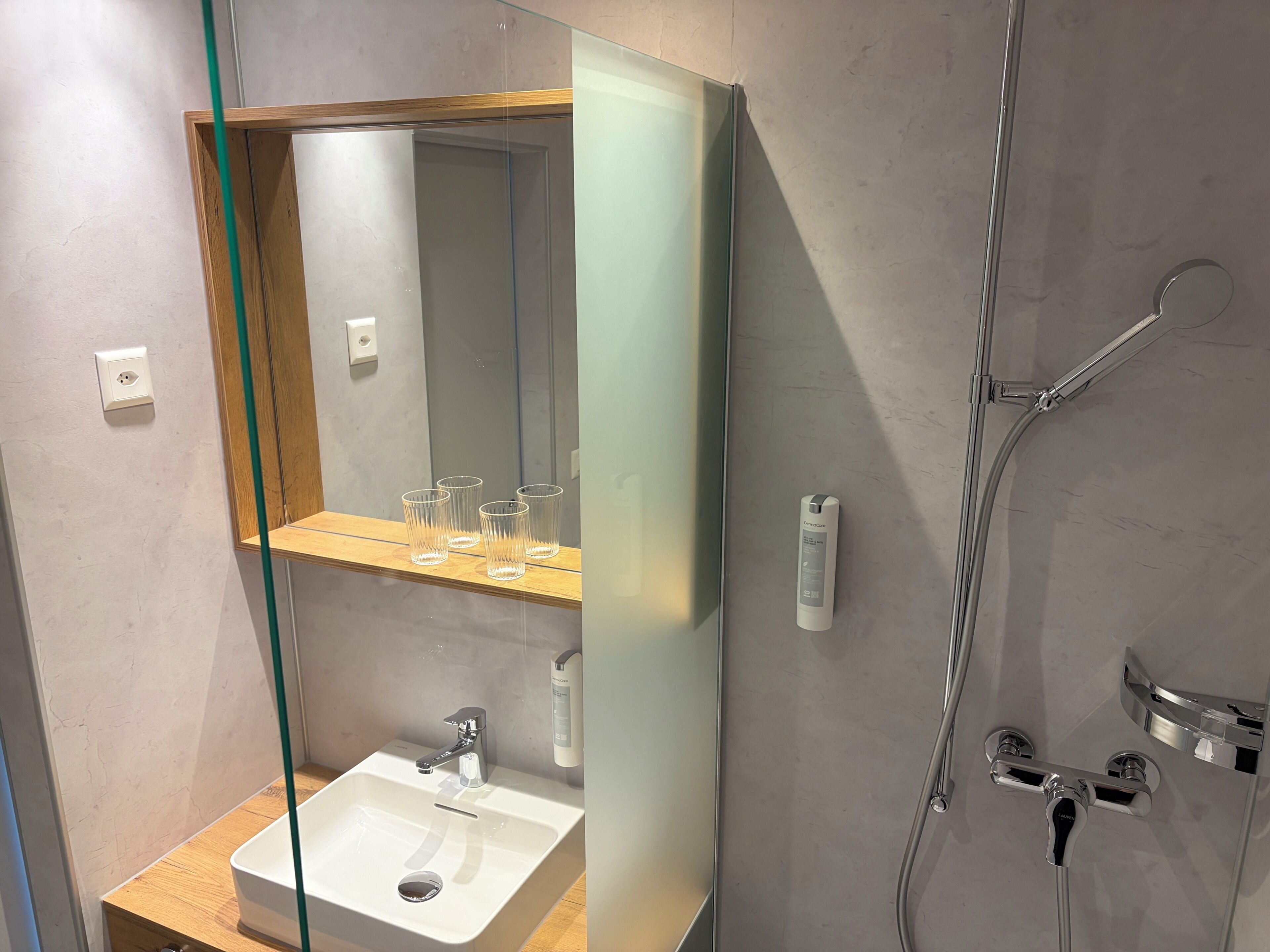 A modern bathroom with a glass shower enclosure, a wooden vanity with a sink, and a mirror above the vanity.