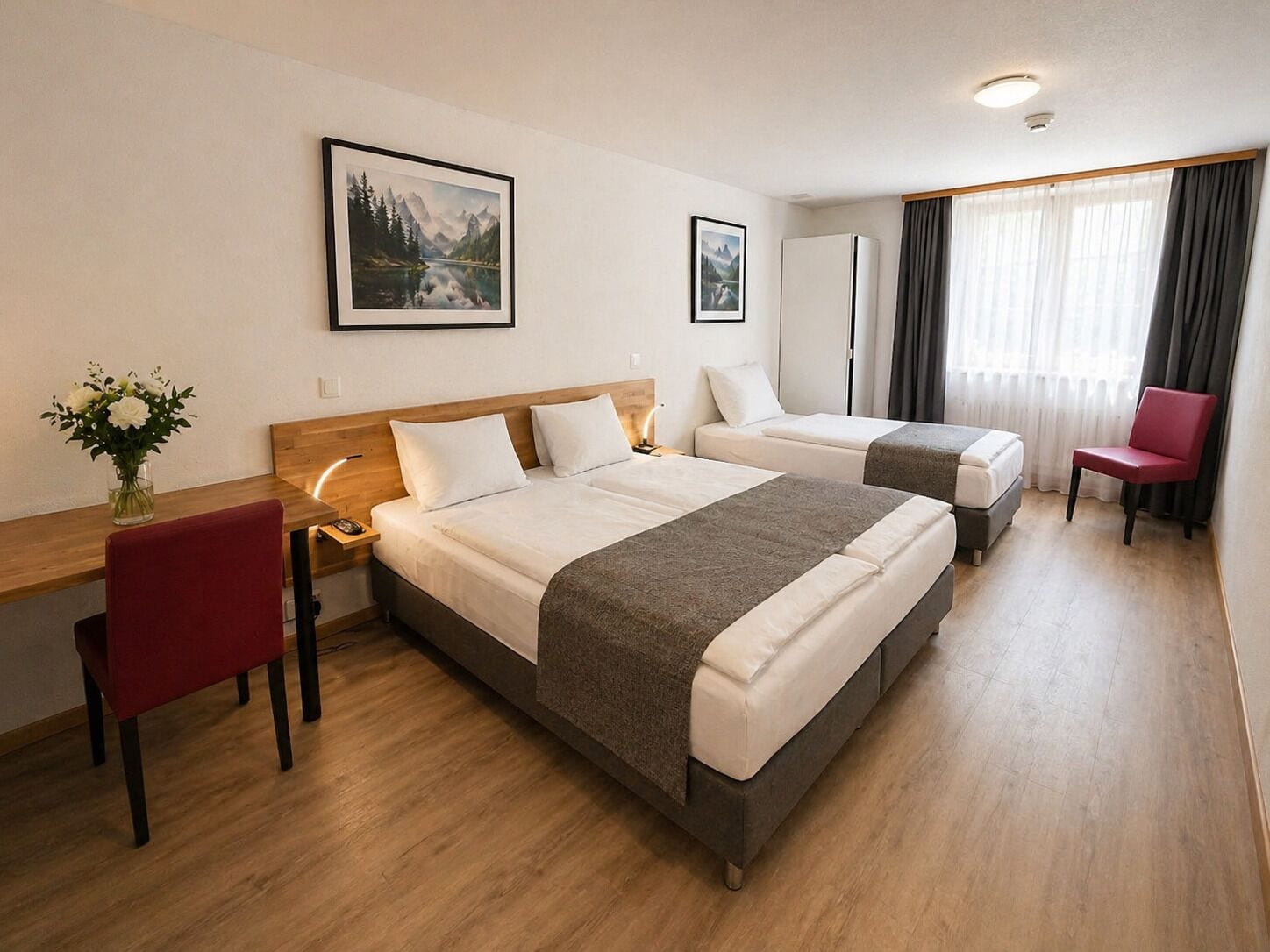 Ein Hotelzimmer mit zwei Betten, einem Schreibtisch, einem Stuhl und einem Fenster mit Vorhängen.