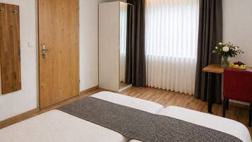 Una habitación de hotel con una cama, una puerta de madera y un escritorio con un florero.