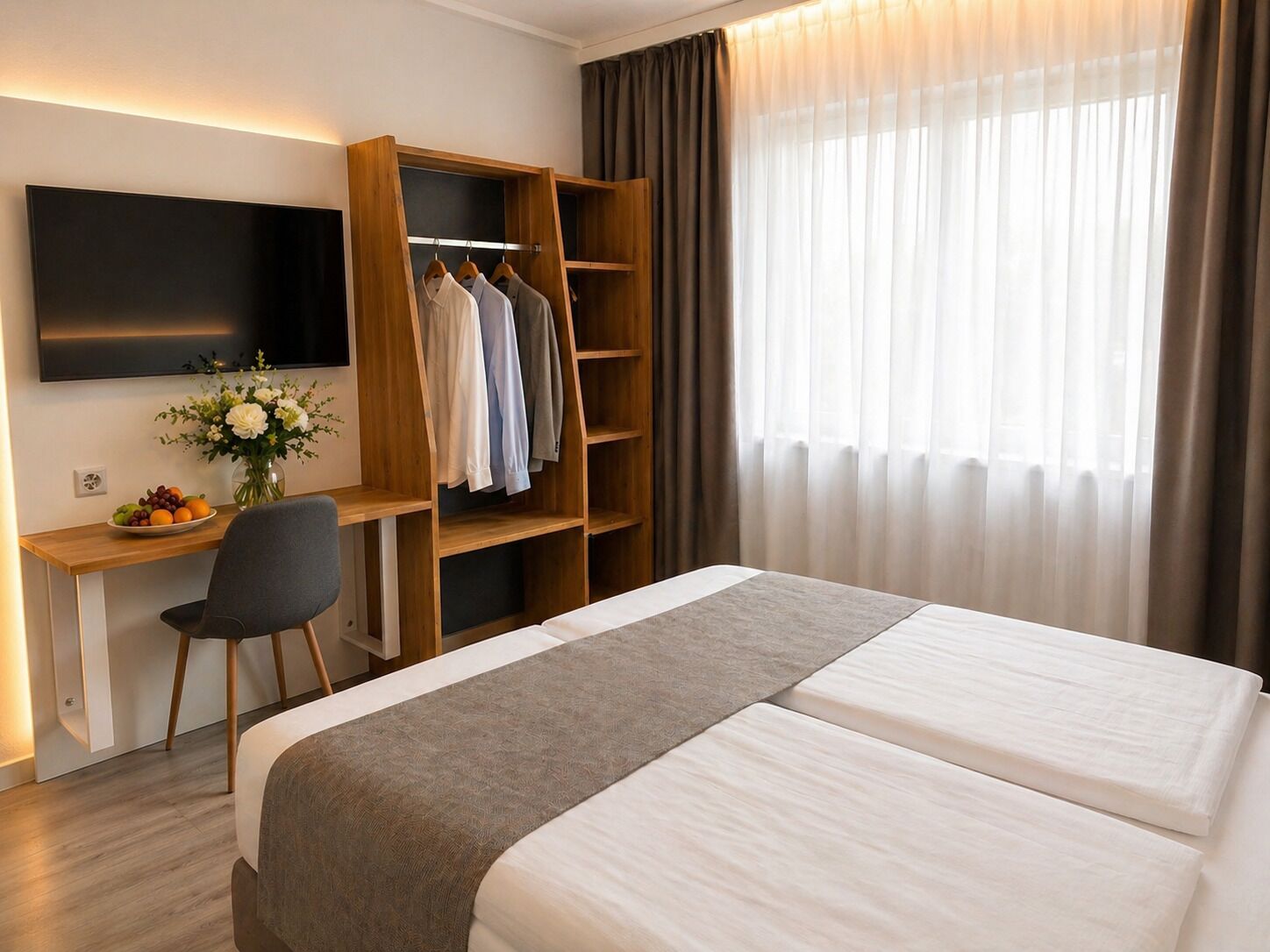 A hotel room with a bed, a desk with a chair, a wardrobe, and a TV.