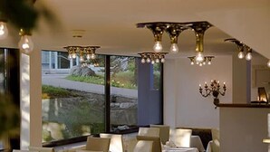 Un restaurante con mesas dispuestas para comer, amplias ventanas y modernas luminarias.