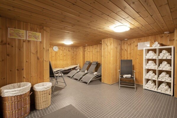 Una sala de sauna con paredes de madera, un reloj y un perchero para toallas.