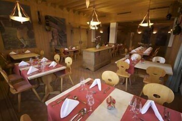 Un restaurante con interiores de madera, varias mesas dispuestas para comer y lámparas colgantes.