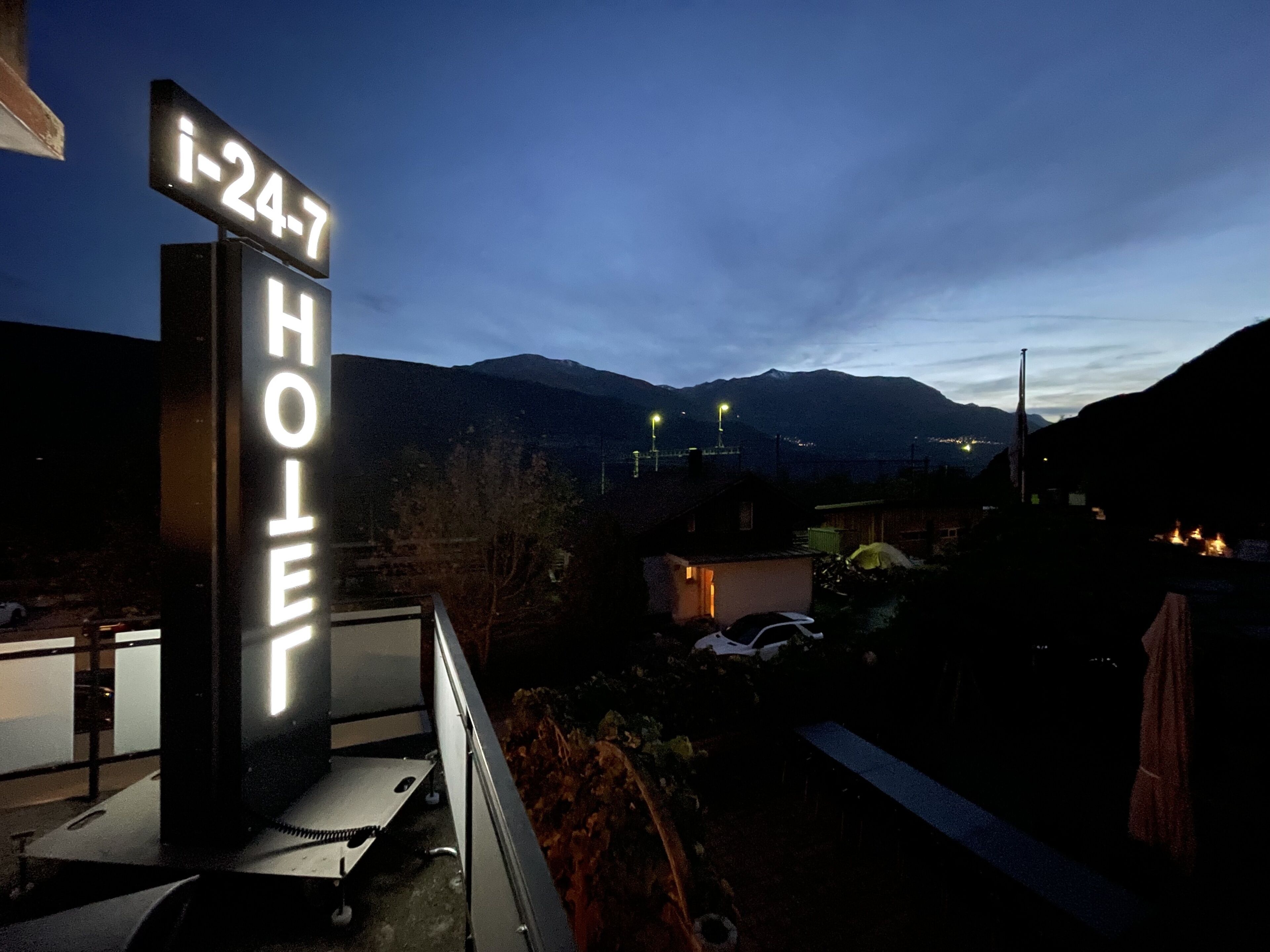 A hotel sign with the number "i-24-7" and the word "HOTEL" illuminated against a night sky.
