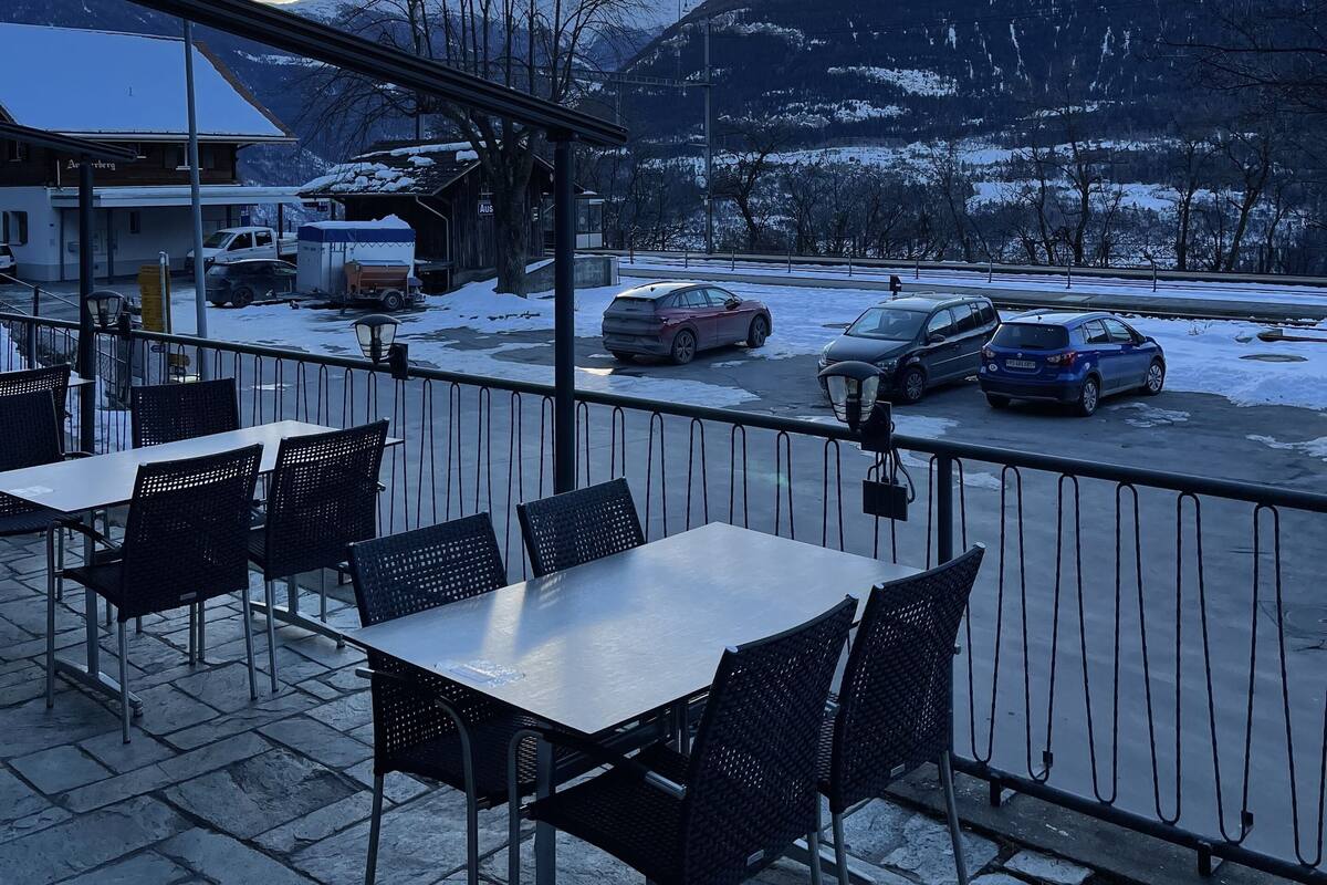 Un espace extérieur aménagé avec des tables et des chaises, offrant une vue sur un paysage enneigé et des montagnes.