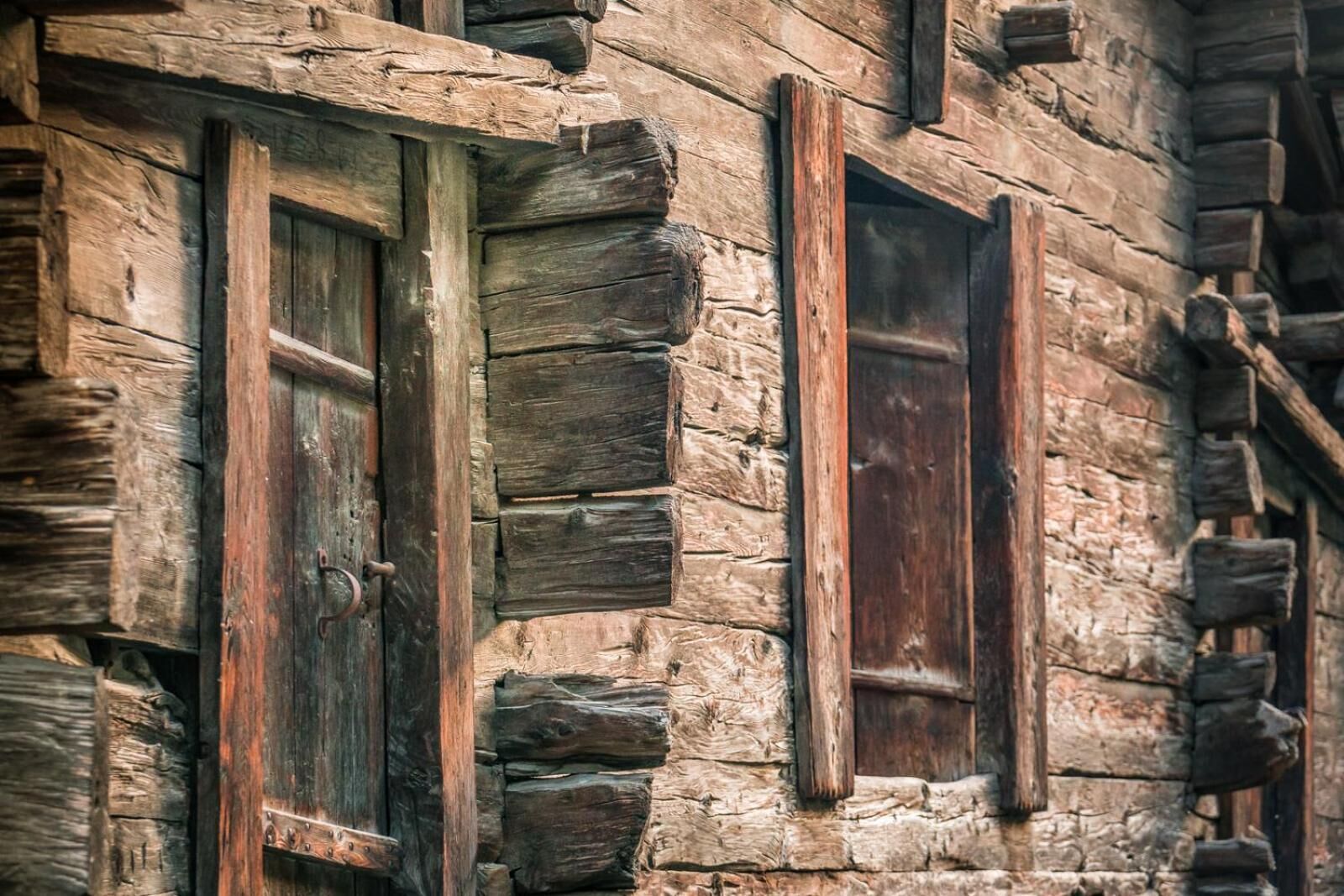 A rustic log cabin with wooden windows and a weathered exterior.