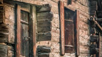 A rustic log cabin with wooden windows and a weathered exterior.