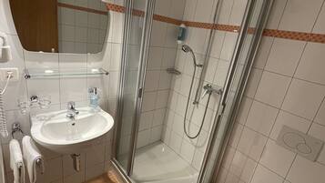 A modern bathroom with a glass-enclosed shower, a sink with a mirror, and a toilet.