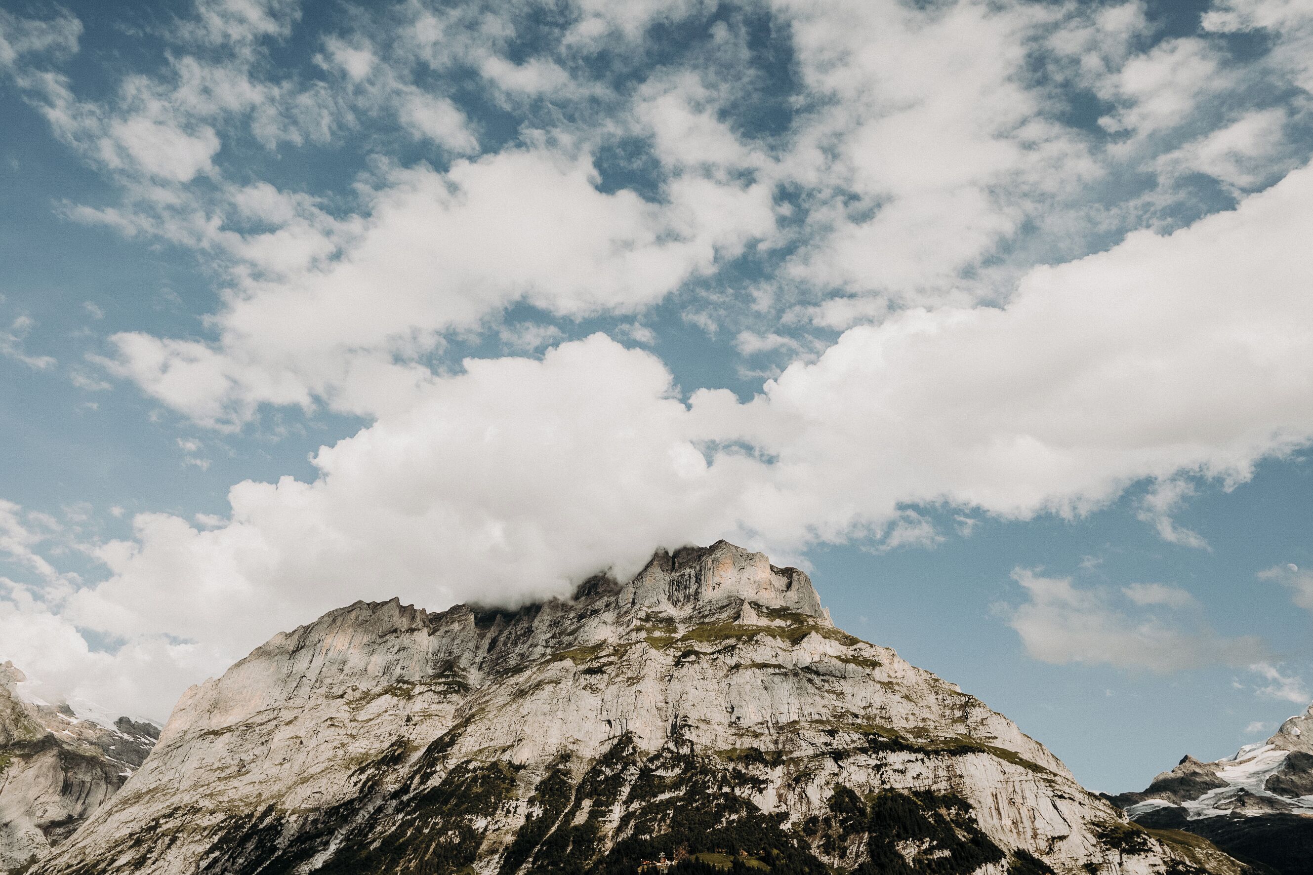 A mountain with a rocky peak and a partly cloudy sky.