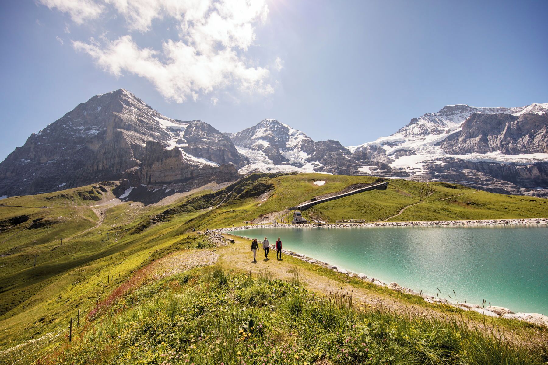 A mountainous landscape with a lake, a small building, and a railway track.
