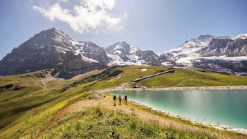 A mountainous landscape with a lake, a small building, and a railway track.