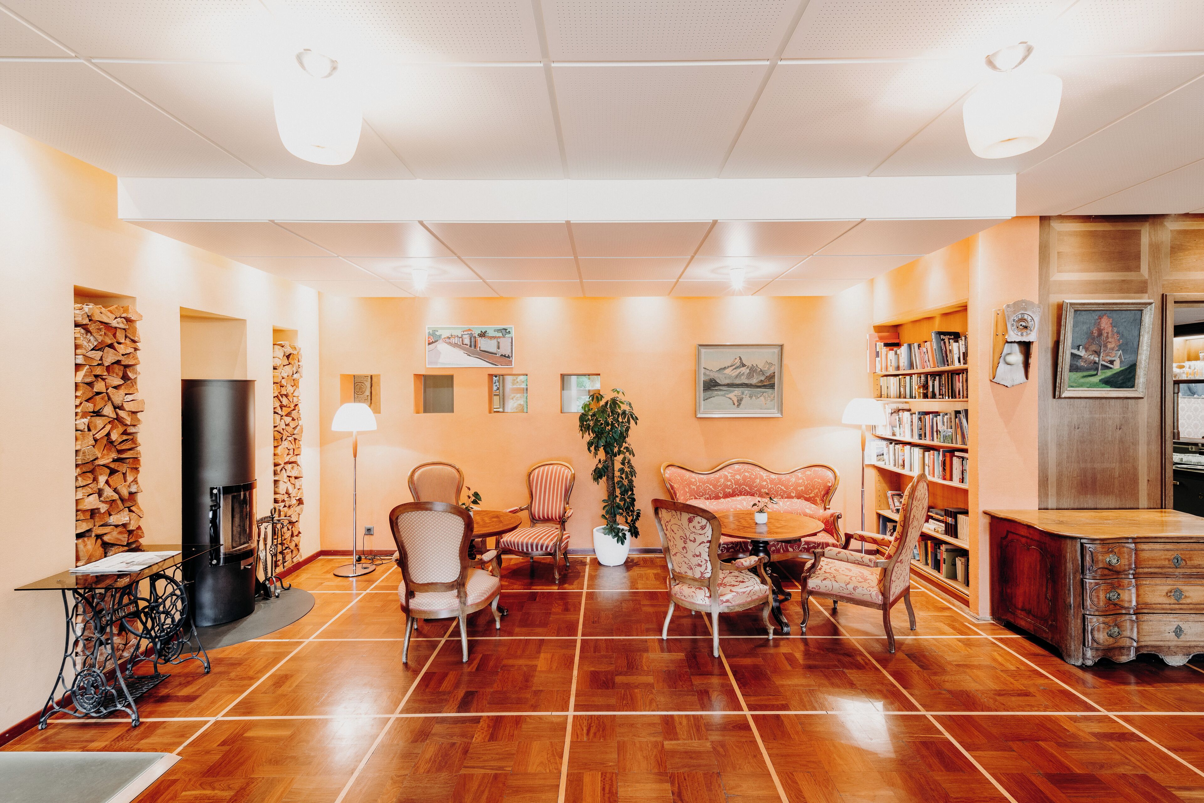 A cozy living room with a fireplace, wooden flooring, and a bookshelf.