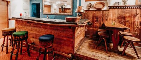 A rustic bar area with wooden stools, a bar counter, and a mirror above the counter.