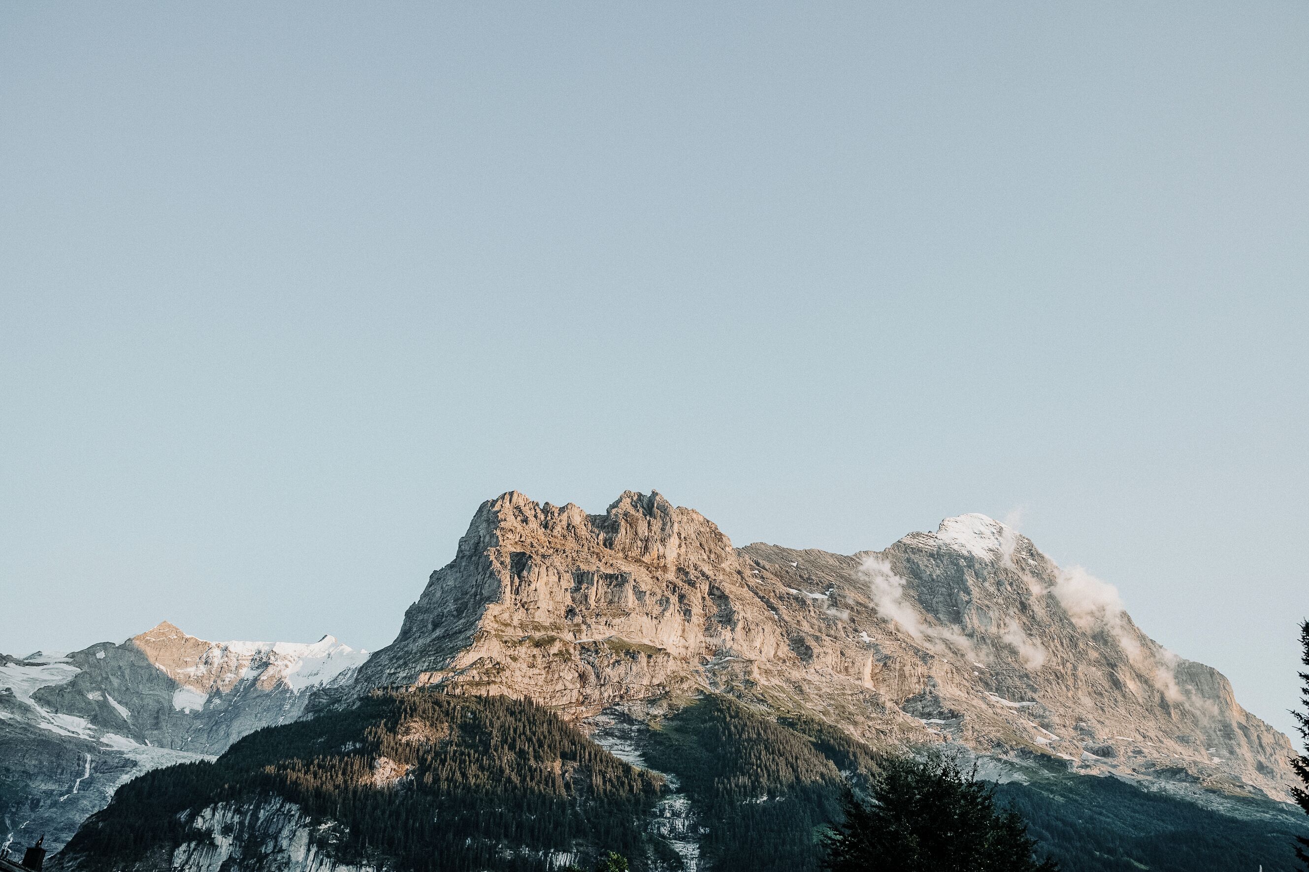 Eine Berglandschaft mit einem markanten Felsen und bewaldeten Hängen.