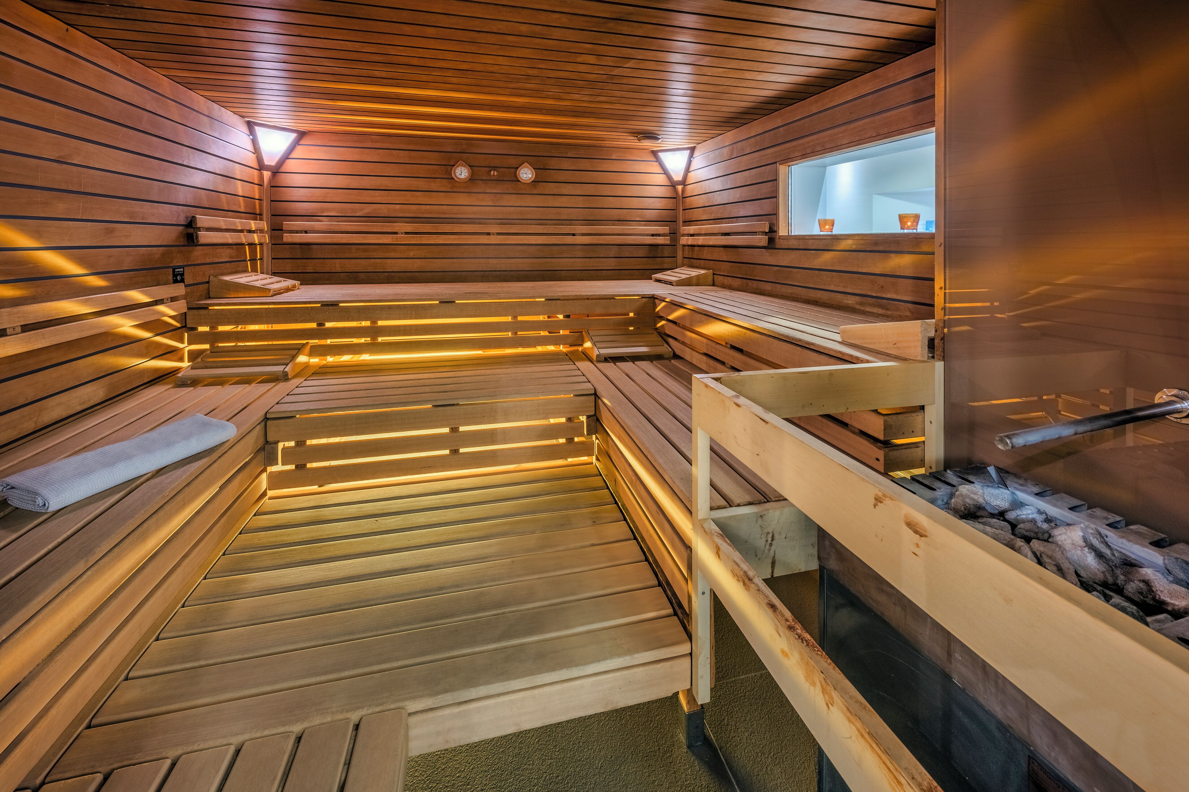 A sauna with wooden benches and benches, a visible water feature, and a window with a view.