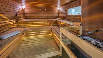 A sauna with wooden benches and benches, a visible water feature, and a window with a view.