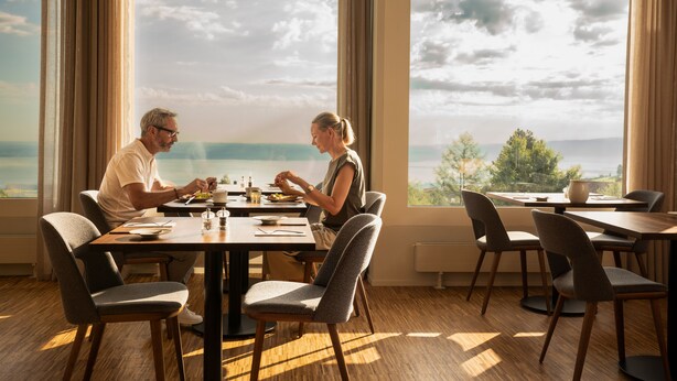 Un comedor con una mesa y sillas, ventanas amplias con vista al mar y un diseño de interiores moderno.