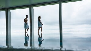 Una habitación con ventanas amplias, piso reflectante y vista al cielo.