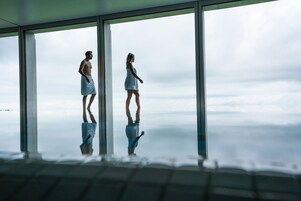 Una habitación con ventanas amplias, piso reflectante y vista al cielo.