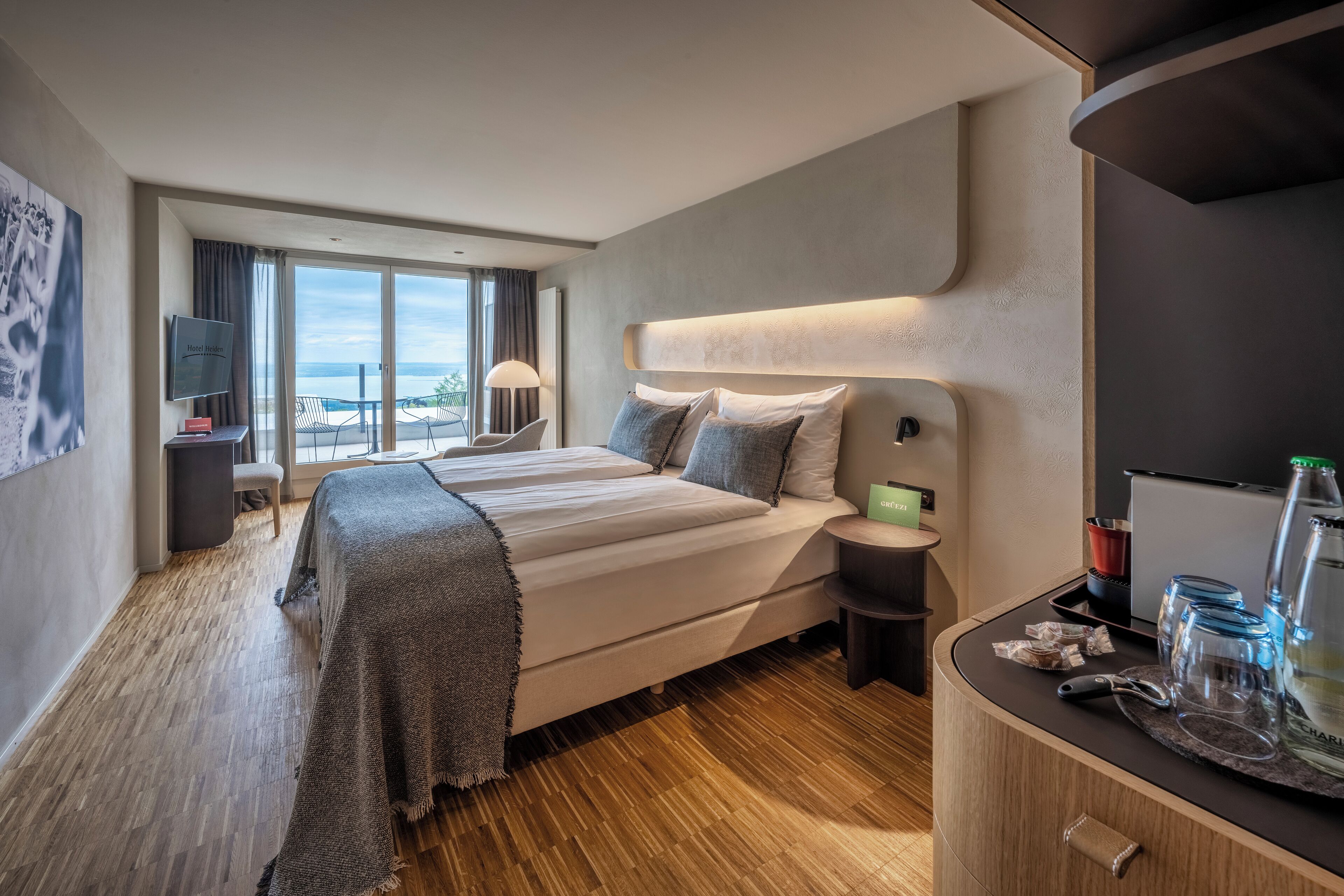 Ein modernes Hotelzimmer mit einem großen Bett, einem Schreibtisch und Meerblick.