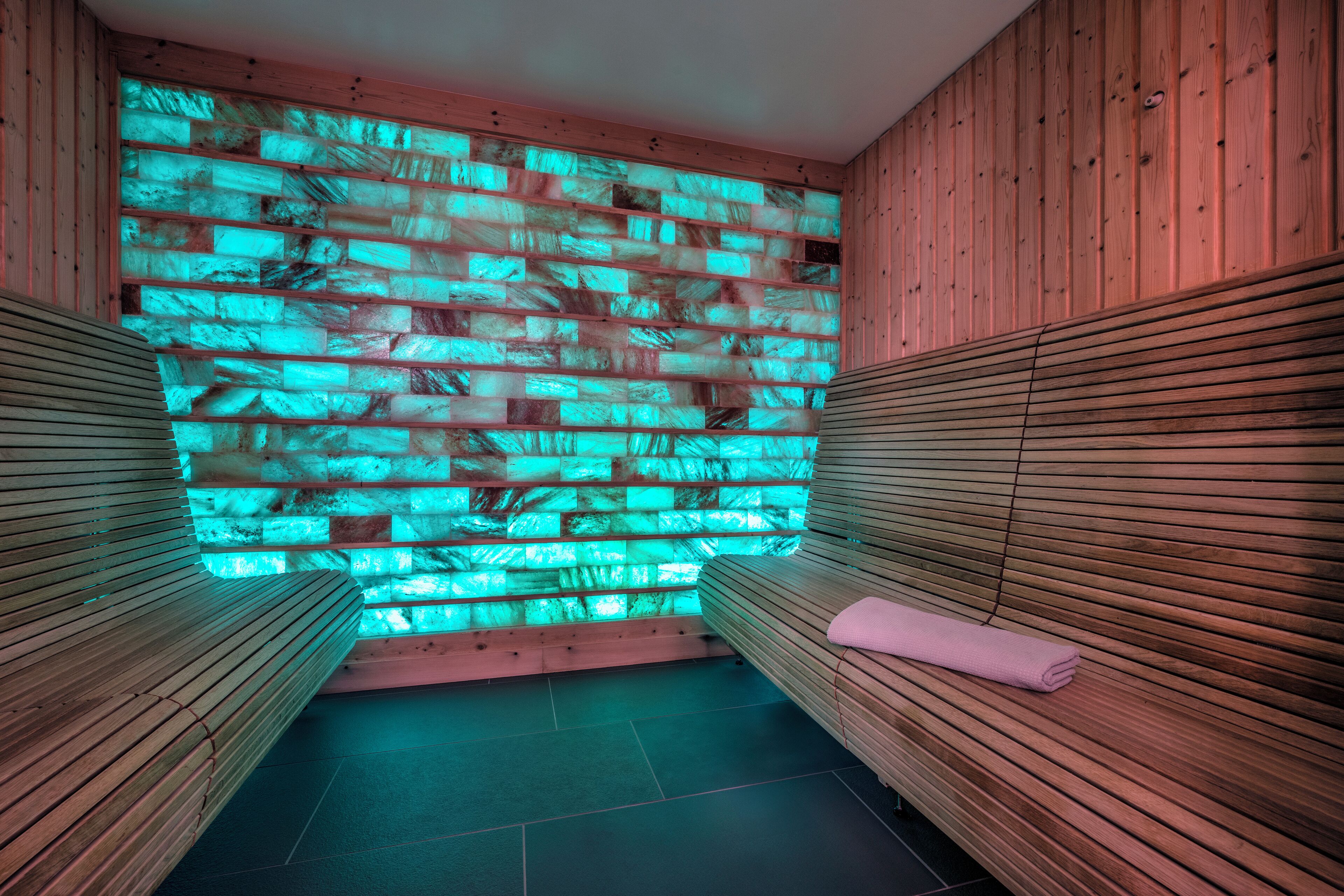 Una sala de sauna con bancos de madera y una pared con textura.