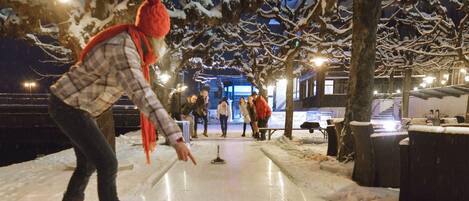 Una persona jugando al herradura sobre una superficie de hielo al aire libre de noche.