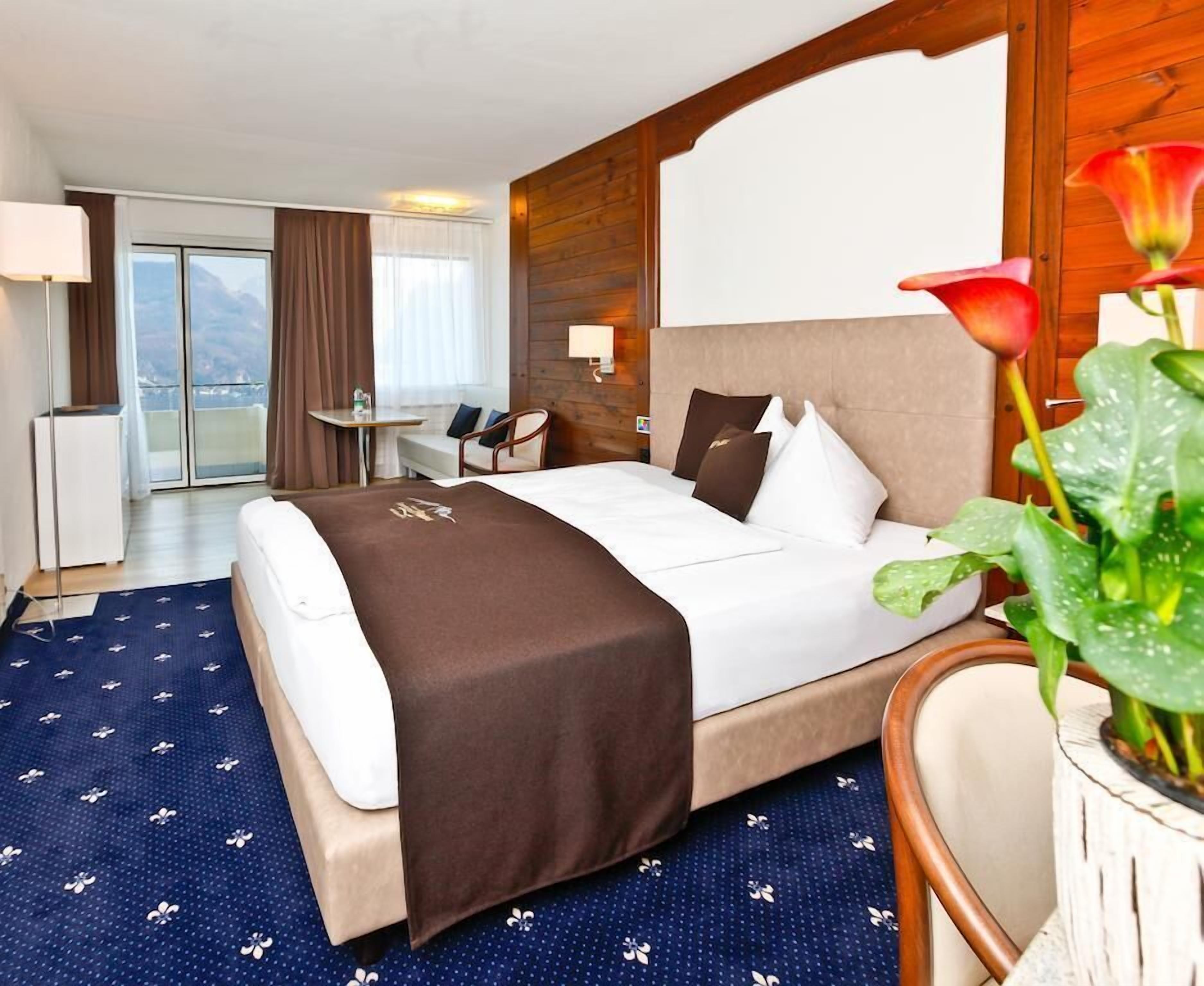 Habitación de hotel con cama, escritorio, silla y vistas al exterior.