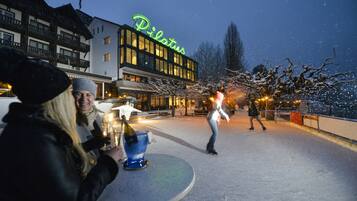 Ein Hotel namens Pilatus mit einer Neonreklame, einem Außenbereich zum Sitzen und verschneiter Umgebung.